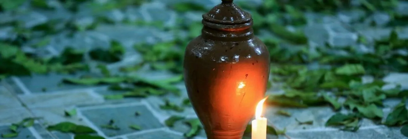 como saber se fizeram macumba para mim: urna com pratos de comida e vela acesa no chão em meio a folhas.