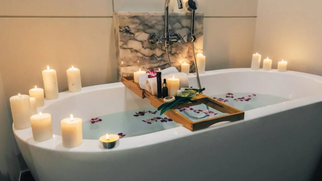 Banheira cheia, com ervas na água e velas acesas em volta