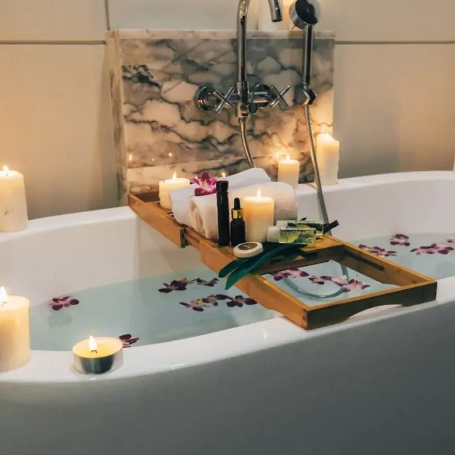 Banheira cheia, com ervas na água e velas acesas em volta