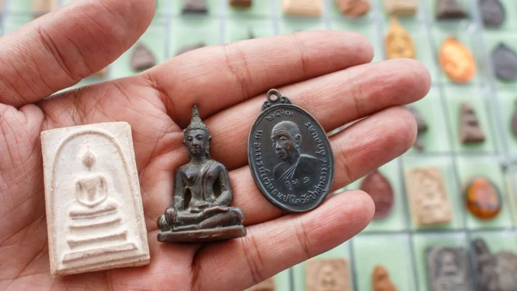 como saber se fizeram macumba para mim: pessoa segurando três amuletos com imagens gravadas sendo um de buda.