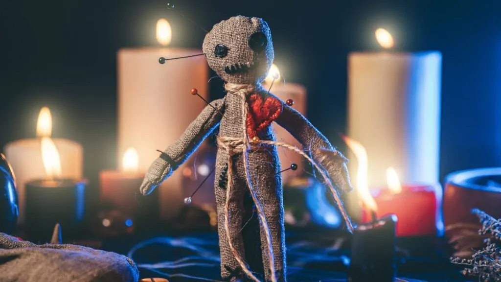 como saber se fizeram macumba para mim: boneco de vudu com velas brancas acesas atrás. 