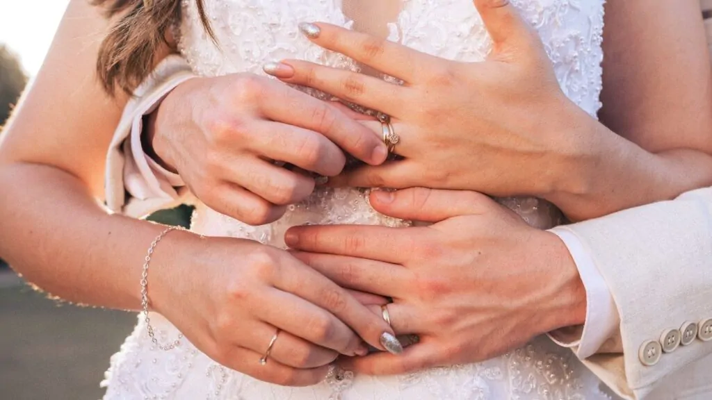 casal de noivos abraçados tocando as alianças um do outro