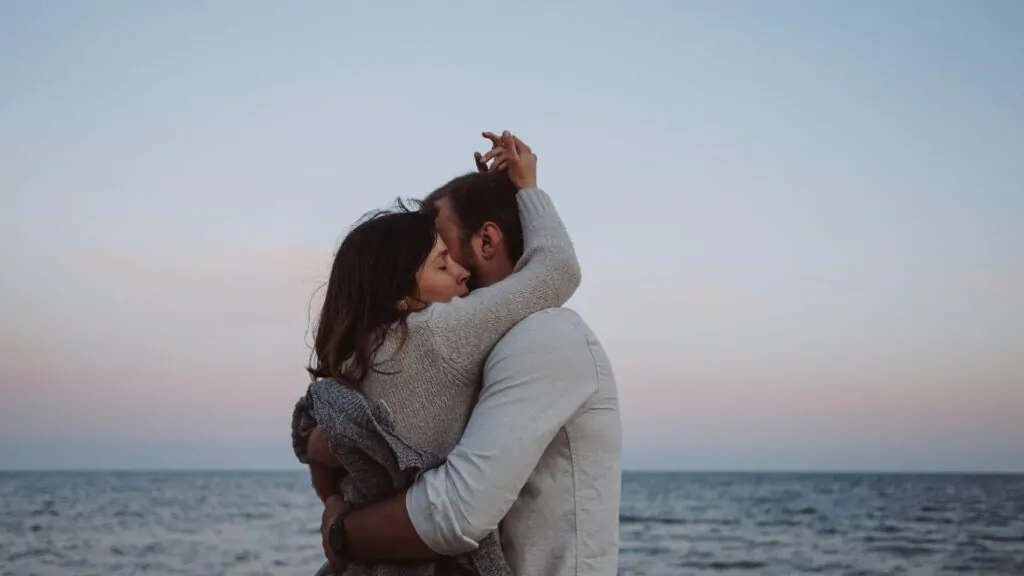 Casal abraçados em frente ao mar.