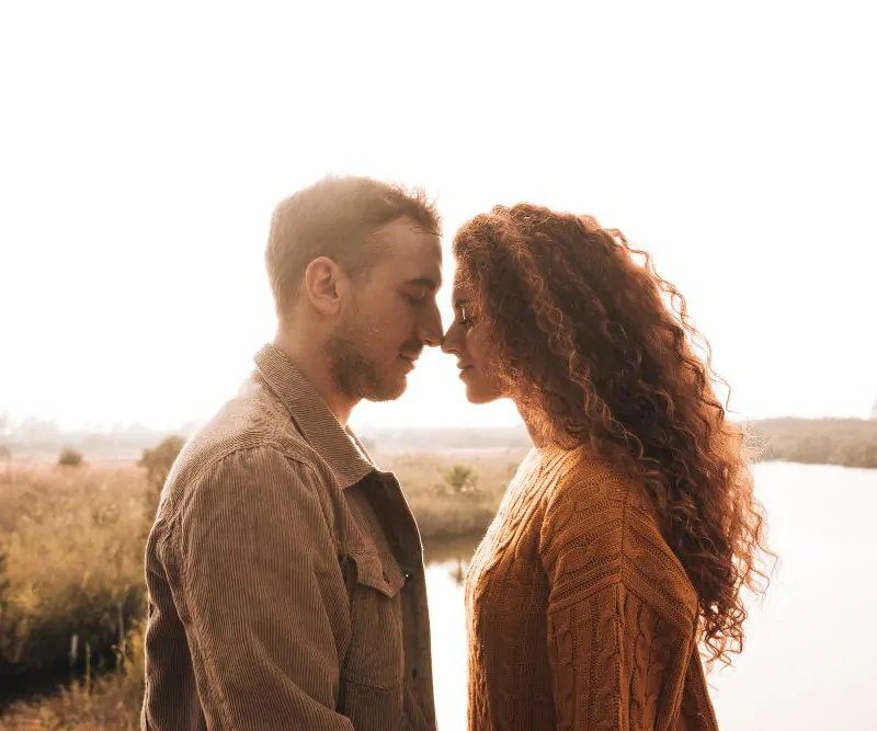 saber se duas pessoas estão destinadas: casal ao ar livre com os rostos próximos como se fosse se beijar.