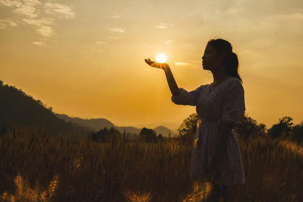 Me apaixonei por um homem casado: mulher no por do sol em uma pose como se estivesse segurando o sol na mão.