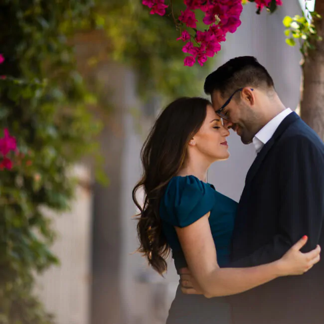 casal abraçados embaixo de uma arvore com flores rosas